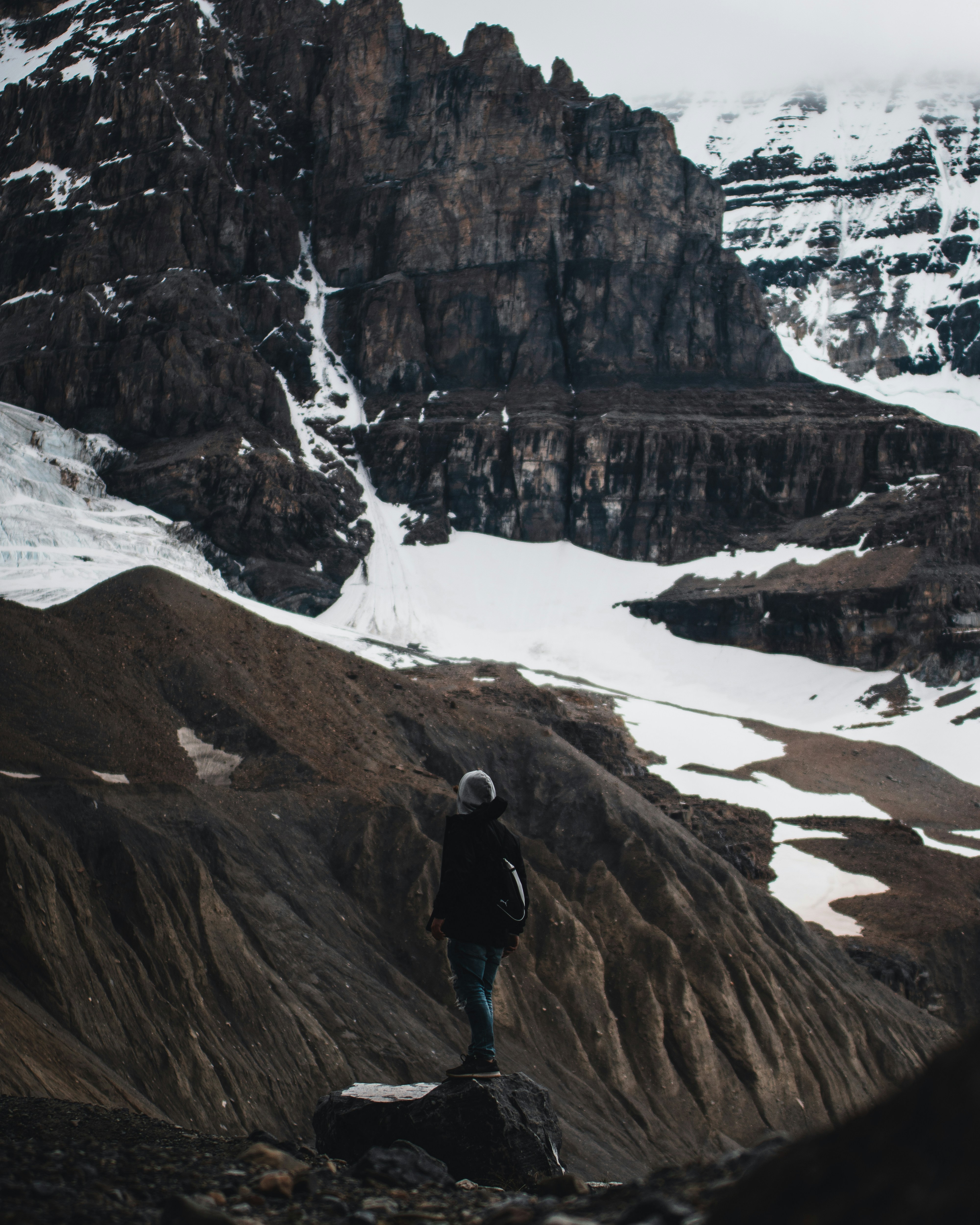 man in black jacket standing on brown rock formation during daytime