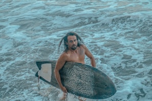 A surfer holding a surf soaps bar with ocean waves rolling behind
