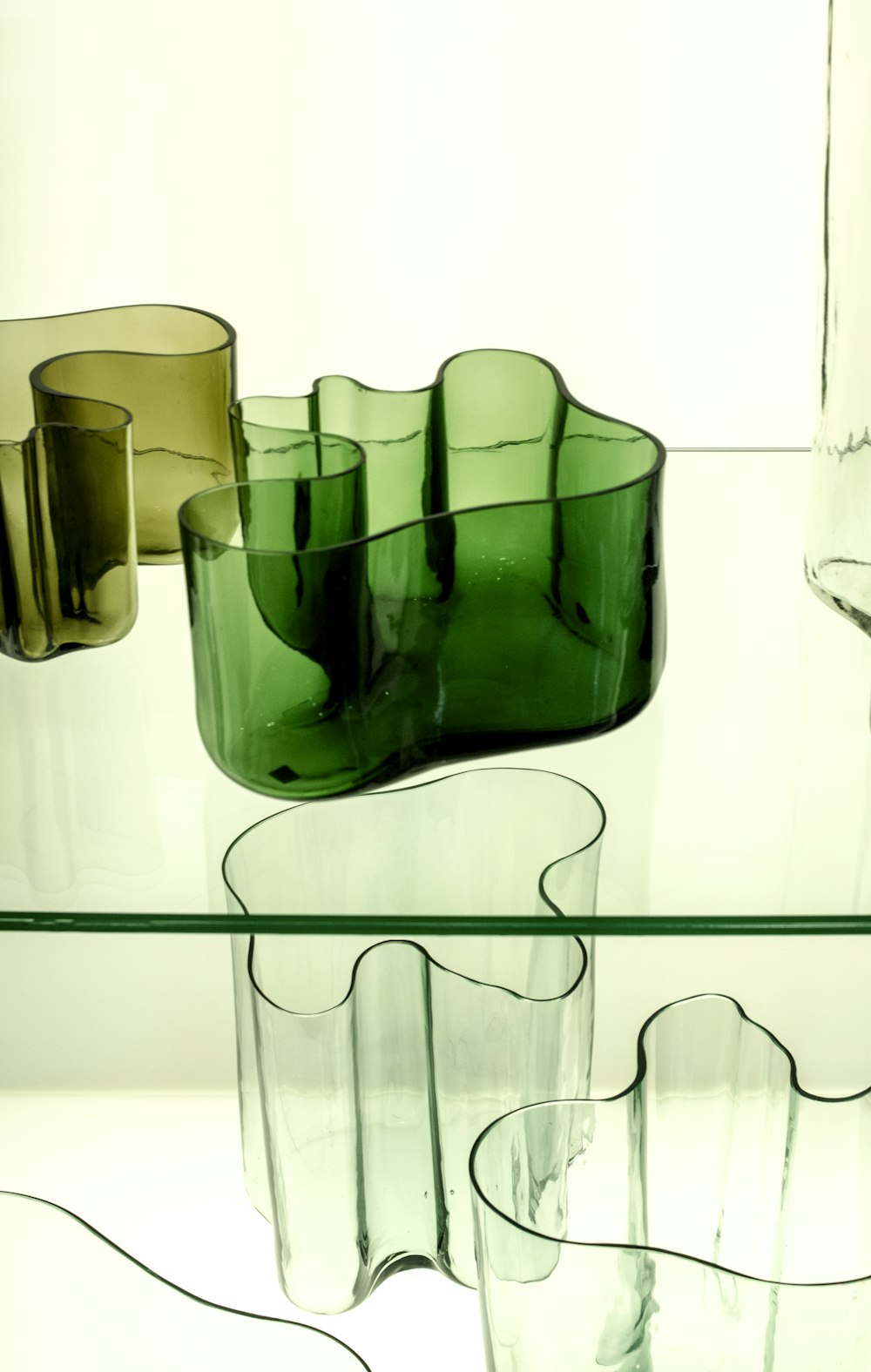 Jarrón de vidrio verde sobre mesa blanca