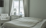 A serene bedroom featuring neutral tones and soft fabrics.