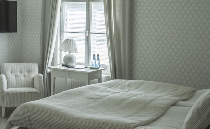 A serene bedroom with soft natural light filtering through sheer curtains, featuring a bedside table with a small diffuser emitting gentle mist.