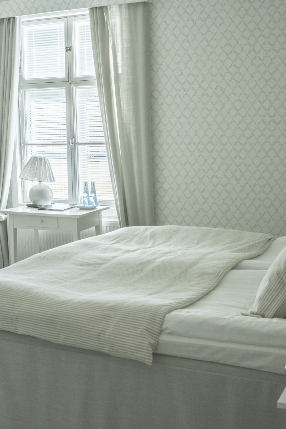 white bed linen near white wooden nightstand