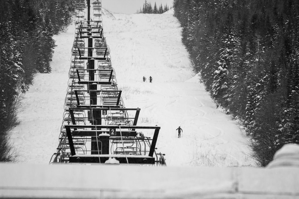 雪に覆われた地面の木製のベンチのグレースケール写真