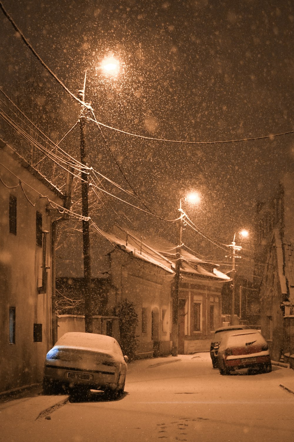 Dos coches aparcados en una calle nevada por la noche