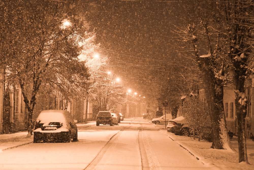 a snowy street with cars parked on the side of it