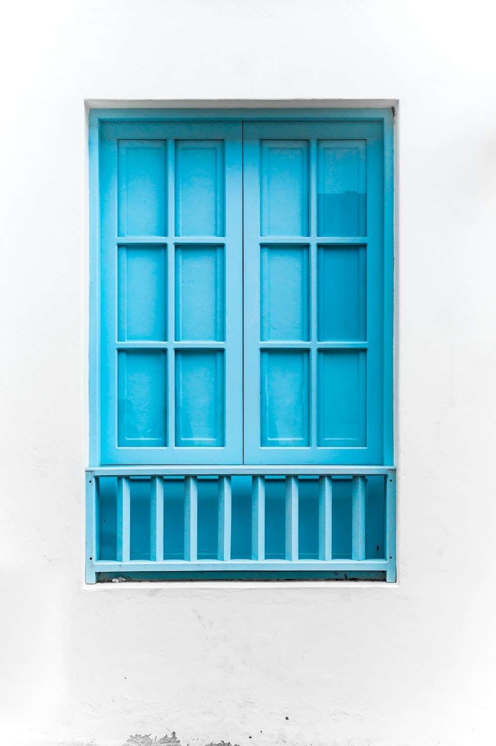 blue wooden window on white concrete wall