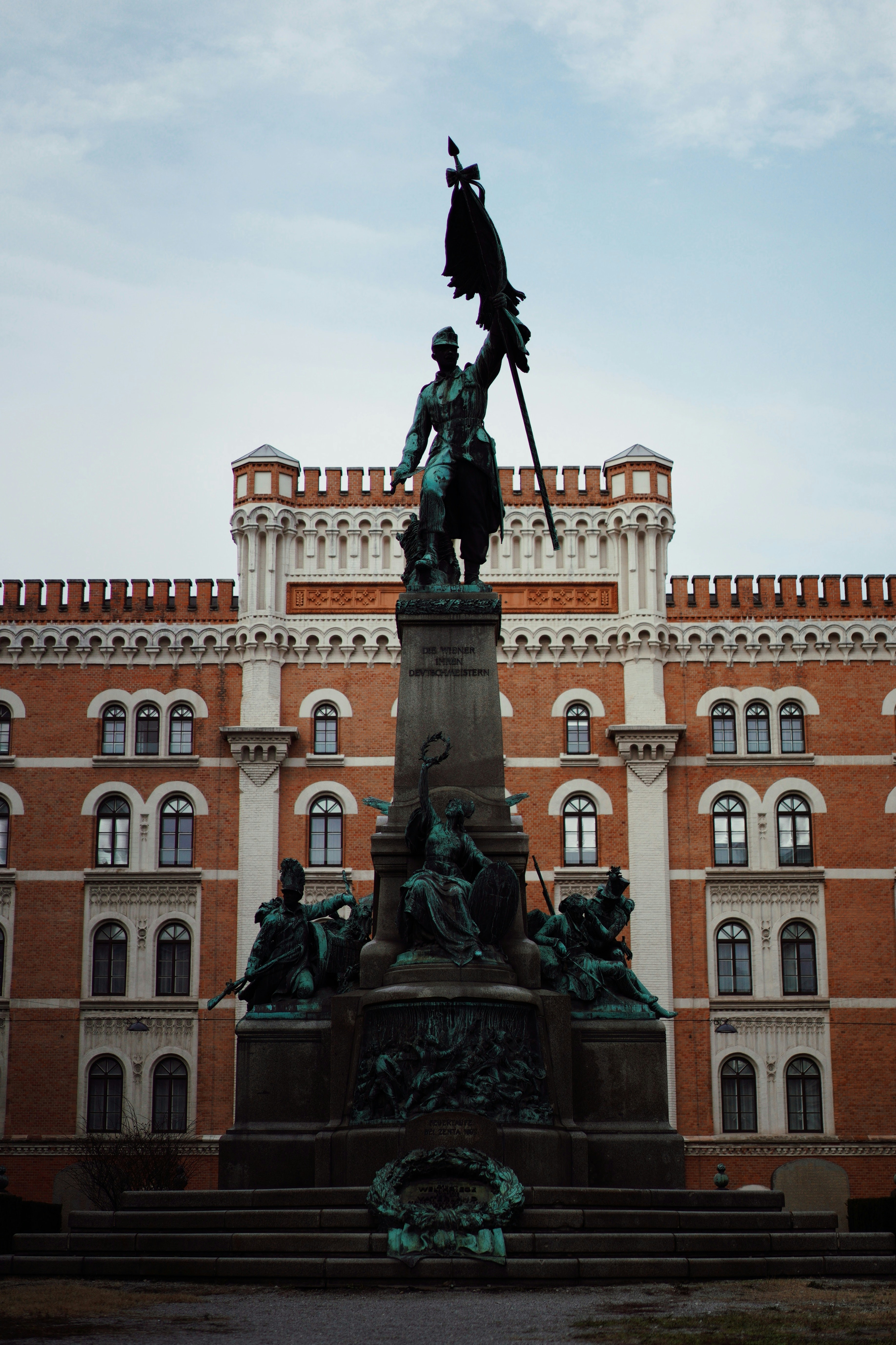 black statue of man holding a flag of us a near beige concrete building during