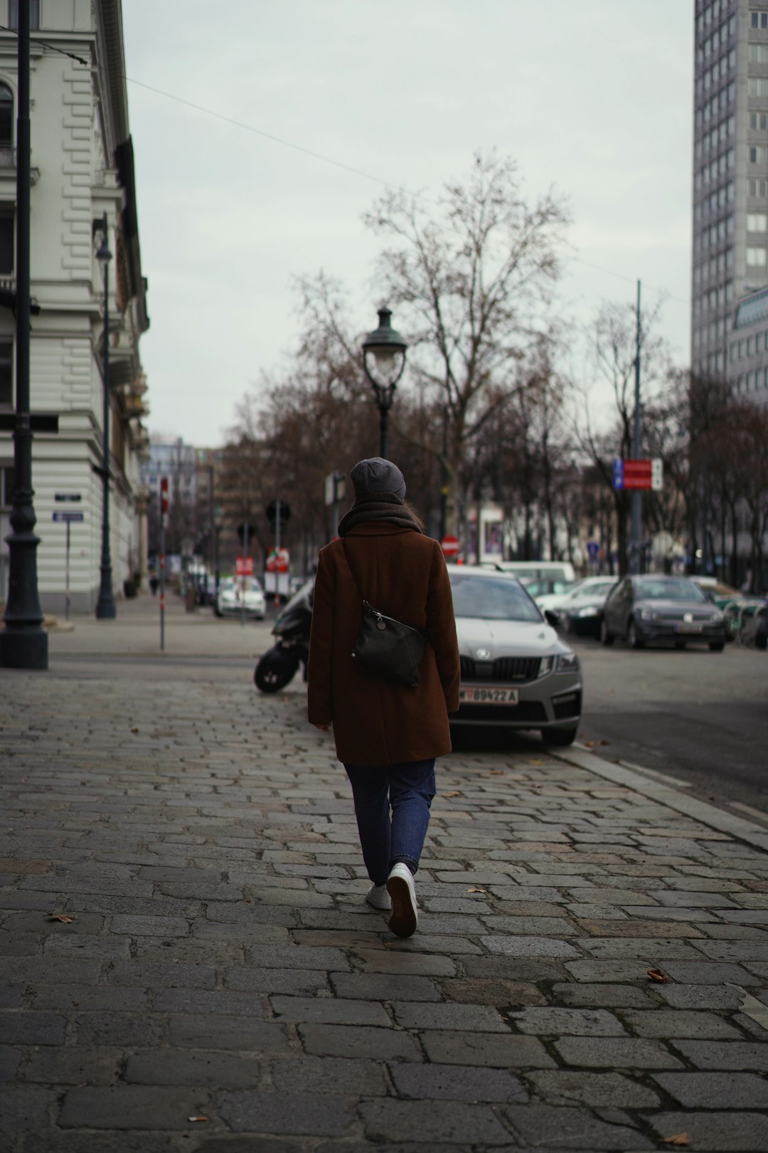 man in brown jacket walking on sidewalk during daytime