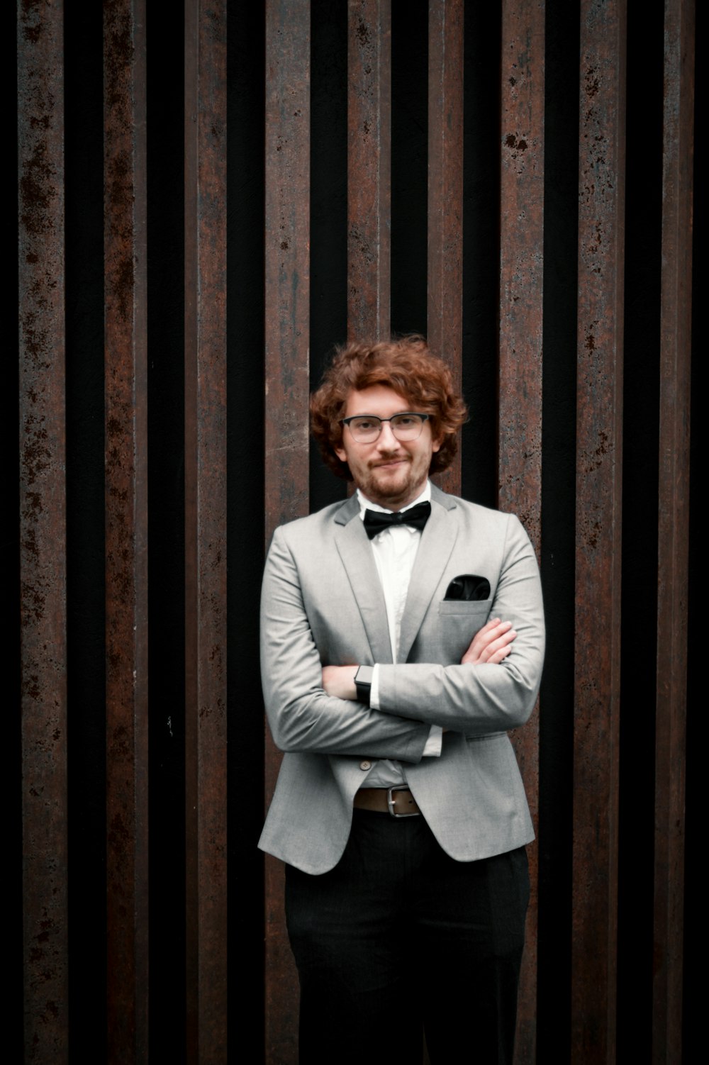 man in white suit standing beside brown wooden wall