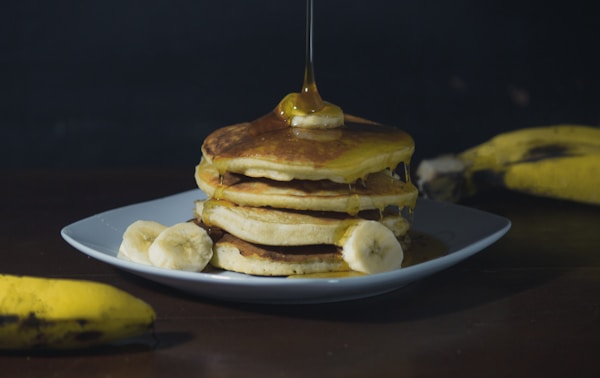 Pancakes with syrup on white ceramic plate