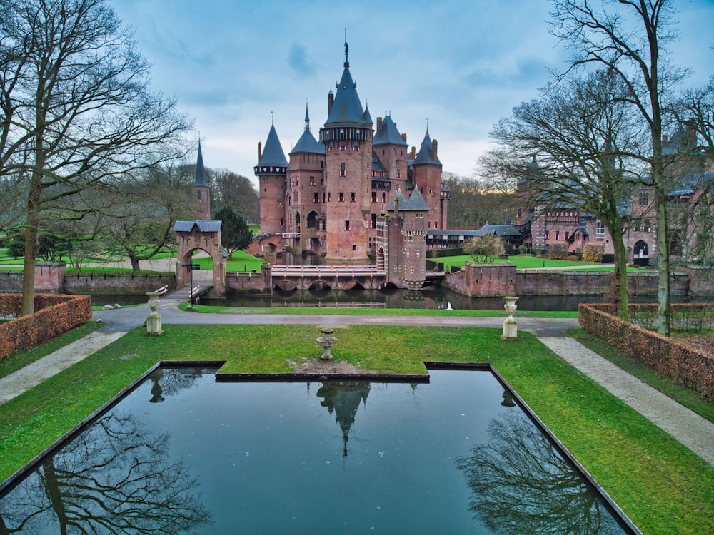 Bâtiment en béton brun et gris près du plan d’eau sous des nuages blancs pendant la journée