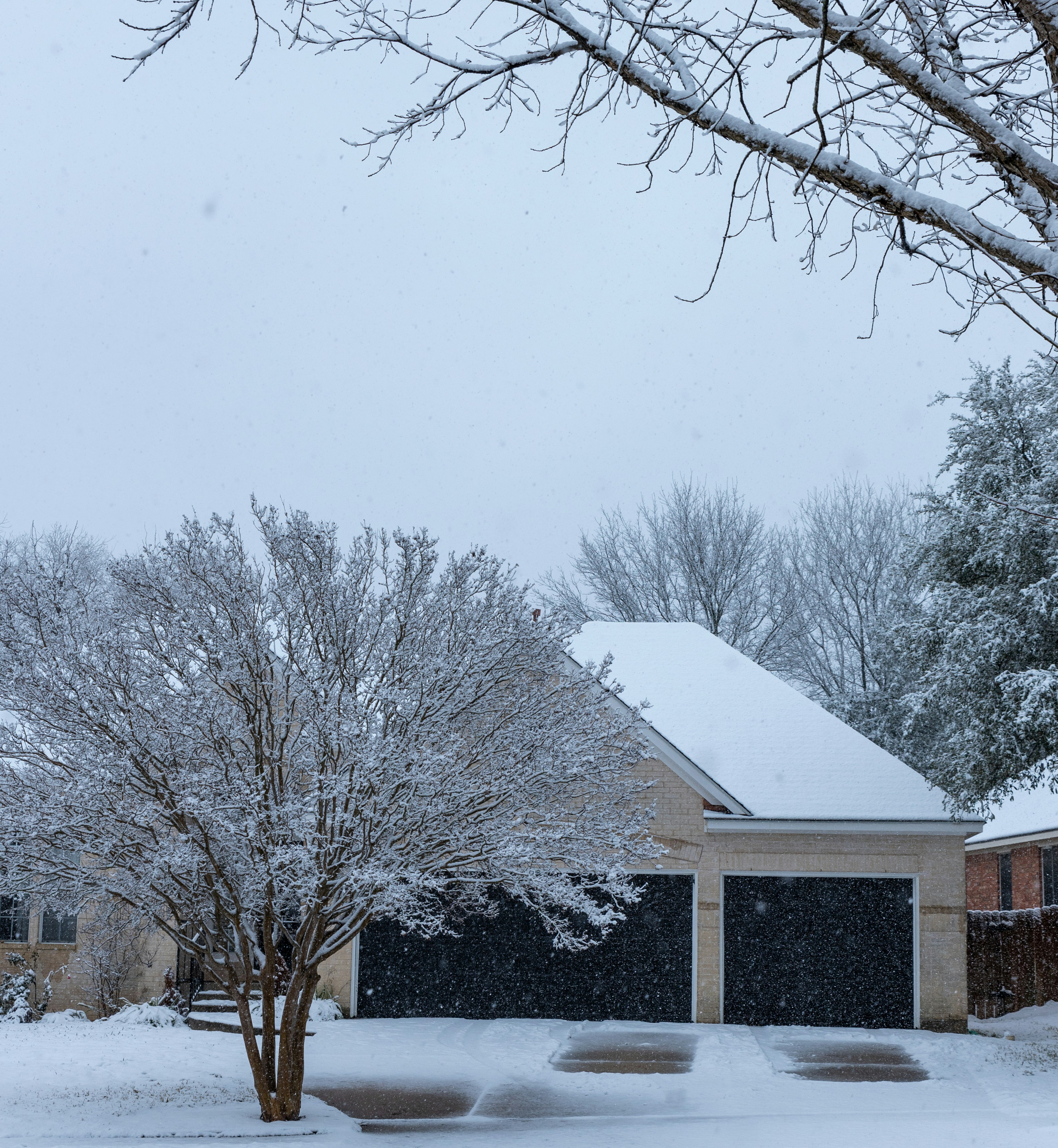 Snow-covered residential driveway with a cleared path to the garage