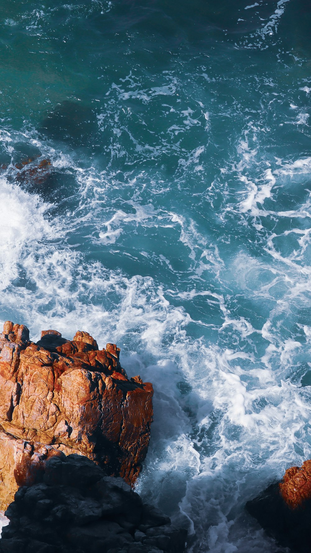 brown rocky mountain beside ocean waves during daytime