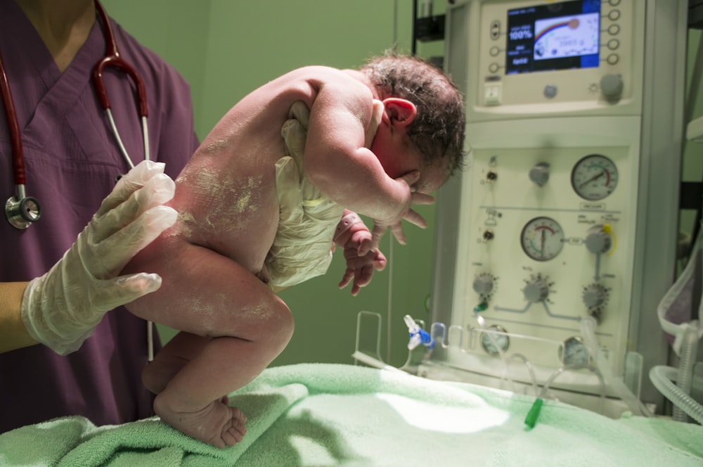 Mann in grünem Peeling-Anzug, der Baby hält