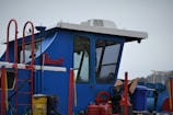 A portable security cabin painted bright blue, stationed at a construction site entrance.