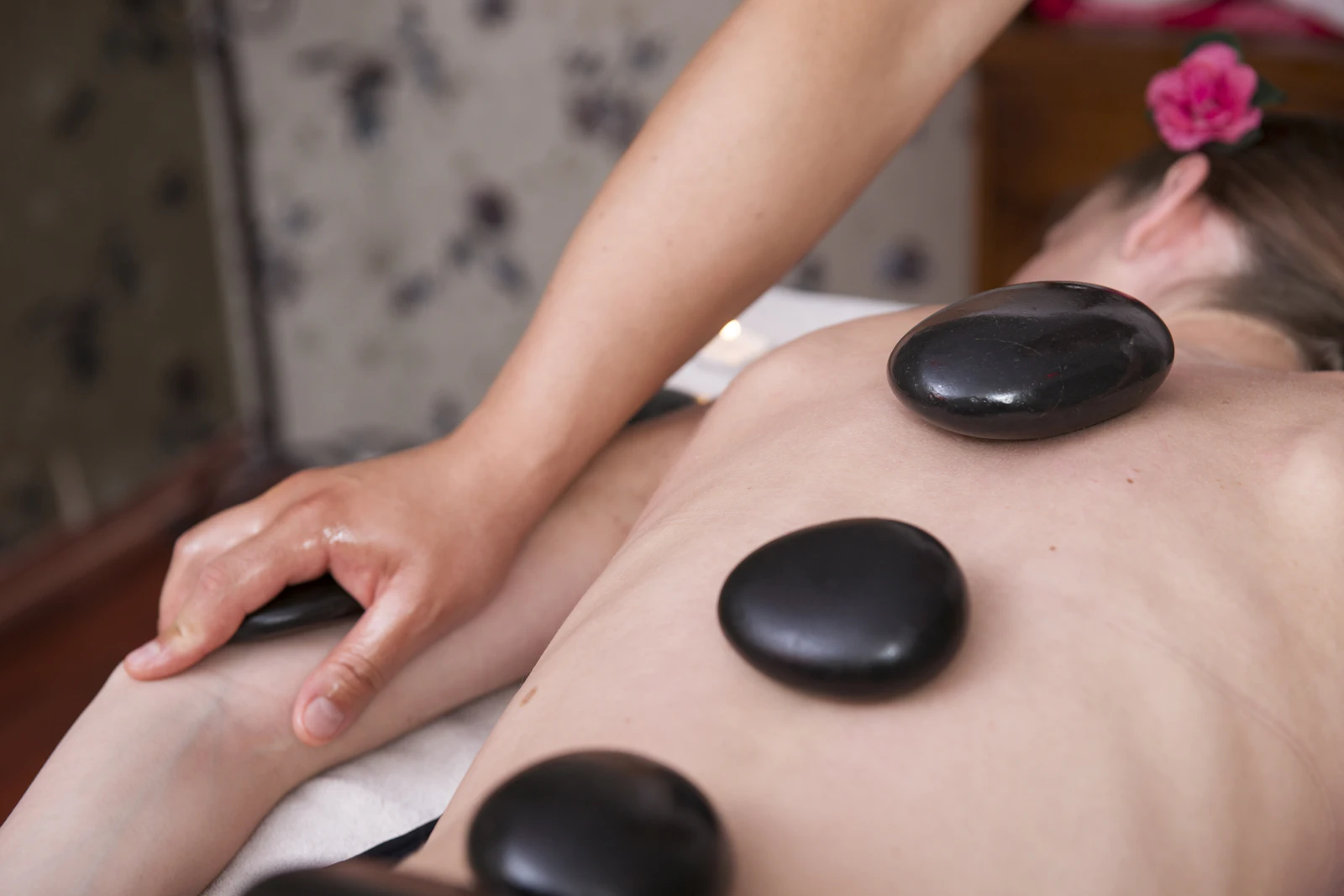 Smooth black stones resting along a guest’s back during a massage