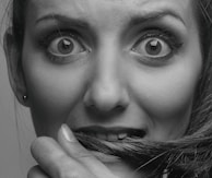 A close-up of eyes wide open in fear, set against a backdrop of swirling shadows and muted reds.