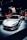 A sleek, silver sports car is prominently displayed under spotlights, surrounded by a crowd in a dimly lit showroom. The background features branding or signage related to the manufacturer.