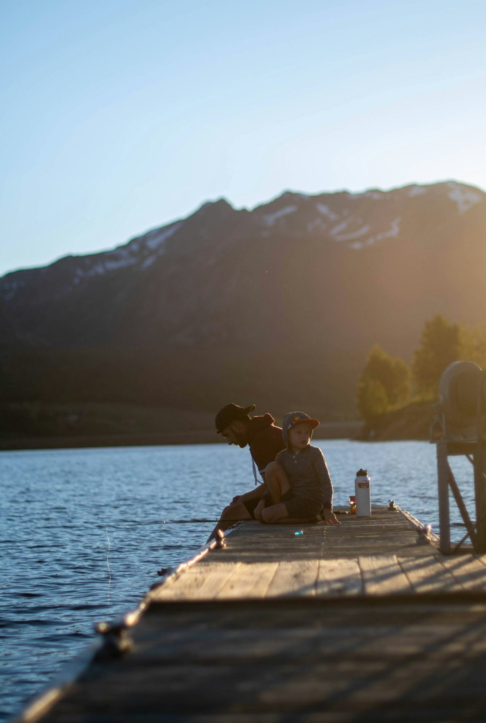 man and woman sitting on wooden dock during daytime