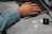 A person wearing a light denim shirt is typing on a laptop placed on a gray table. Next to the laptop, there are multiple memory cards of varying capacities and a black card reader labeled 'INSIGNIA'.