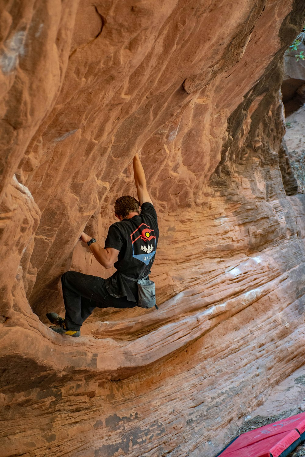 man in black and white adidas hoodie sitting on brown rock formation during daytime