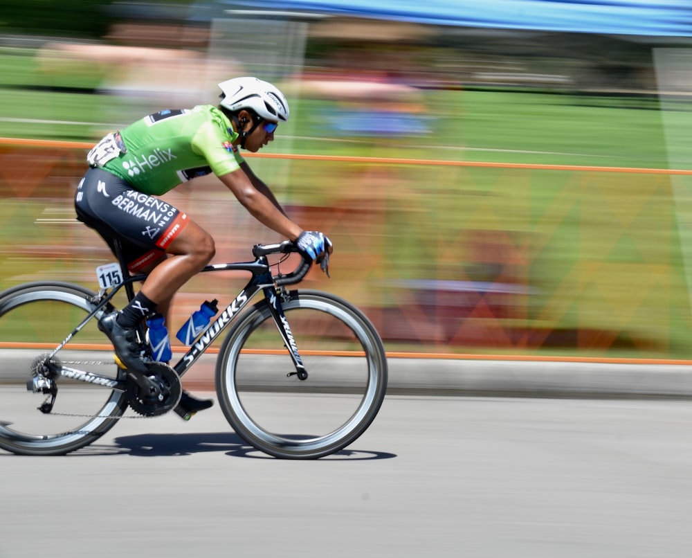 man in green and white bicycle suit riding on black and white road bike