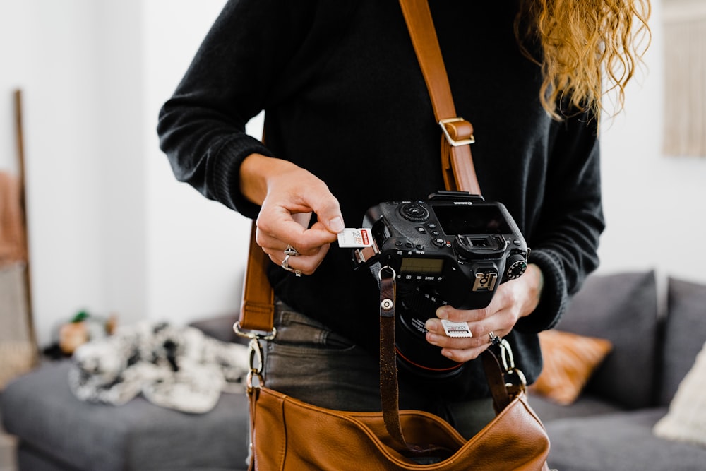 woman in black long sleeve shirt holding black dslr camera