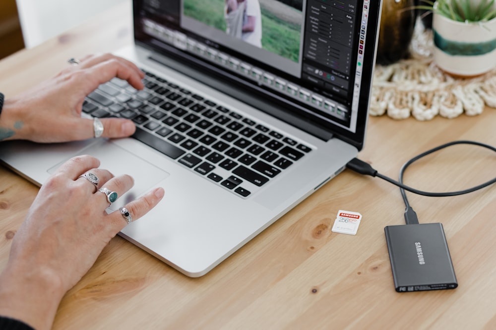 person using macbook pro on brown wooden table