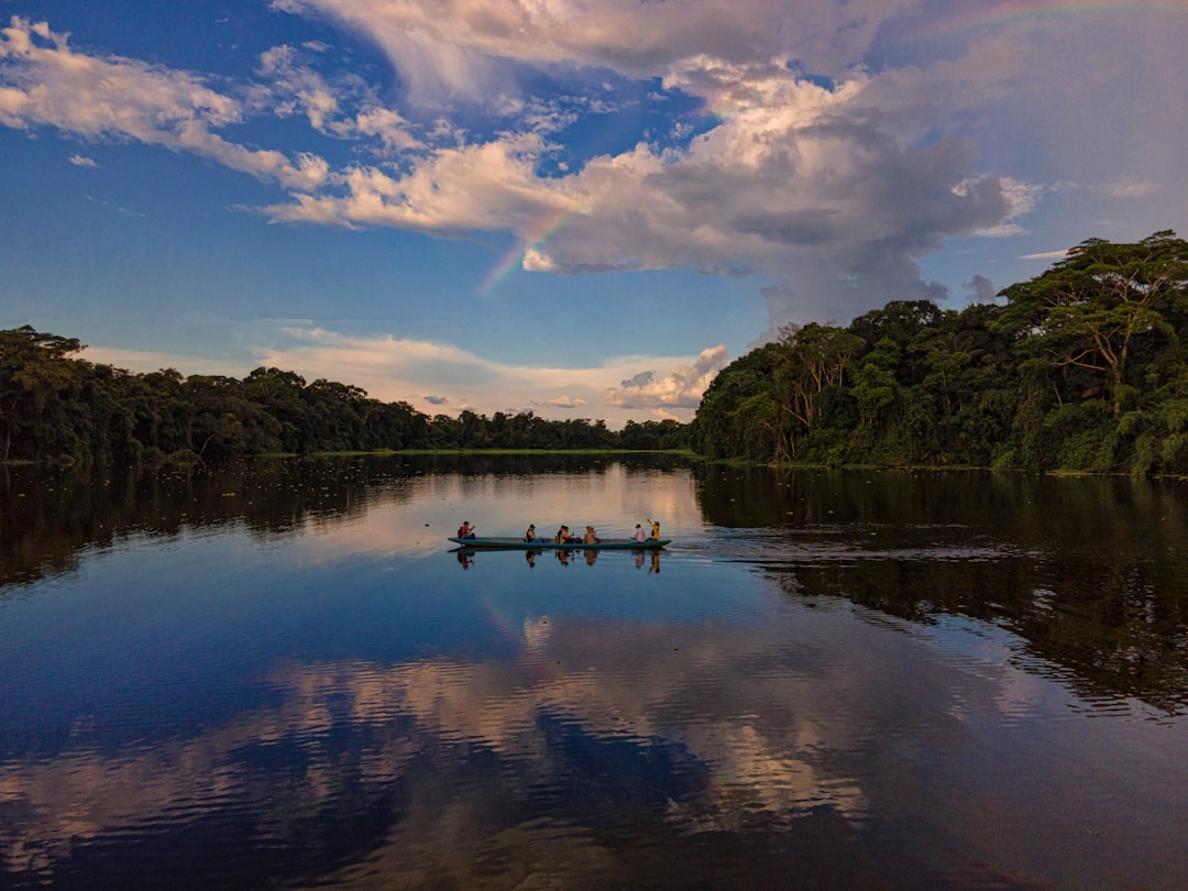 body of water near green trees under blue sky and white clouds during daytime