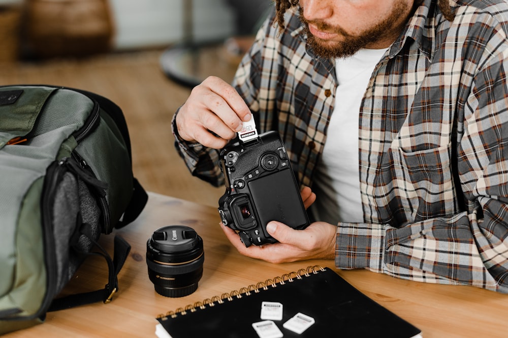 man in black and white plaid dress shirt holding black dslr camera