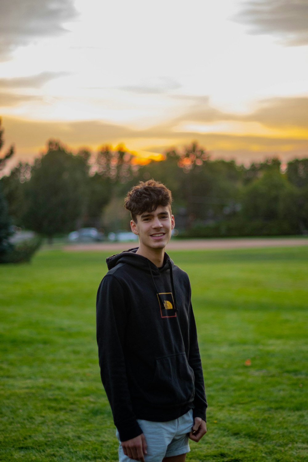 man in black hoodie standing on green grass field during daytime