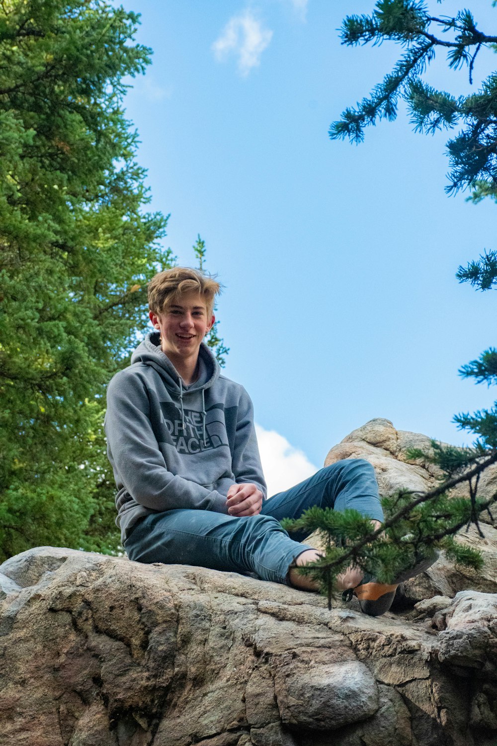 woman in gray hoodie sitting on rock