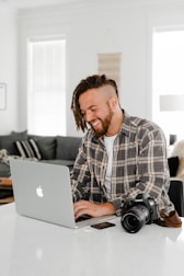 man in blue and white plaid dress shirt using macbook
