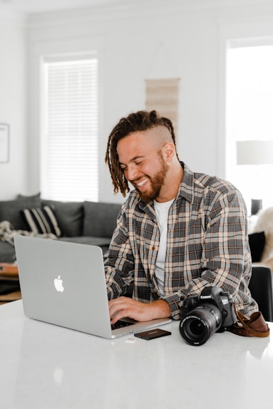 man in blue and white plaid dress shirt using macbook