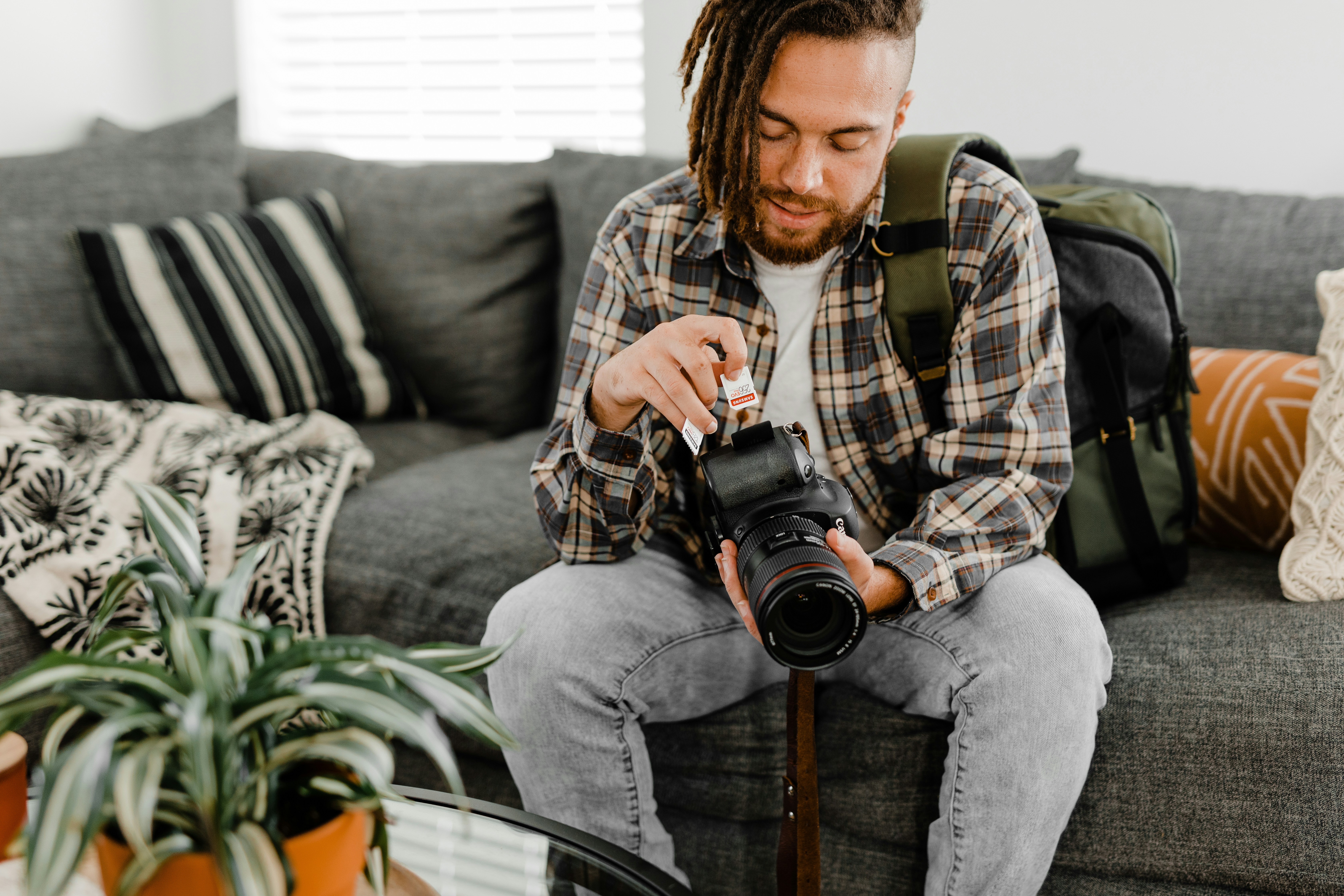 man in brown and white plaid dress shirt and blue denim jeans holding black dslr camera