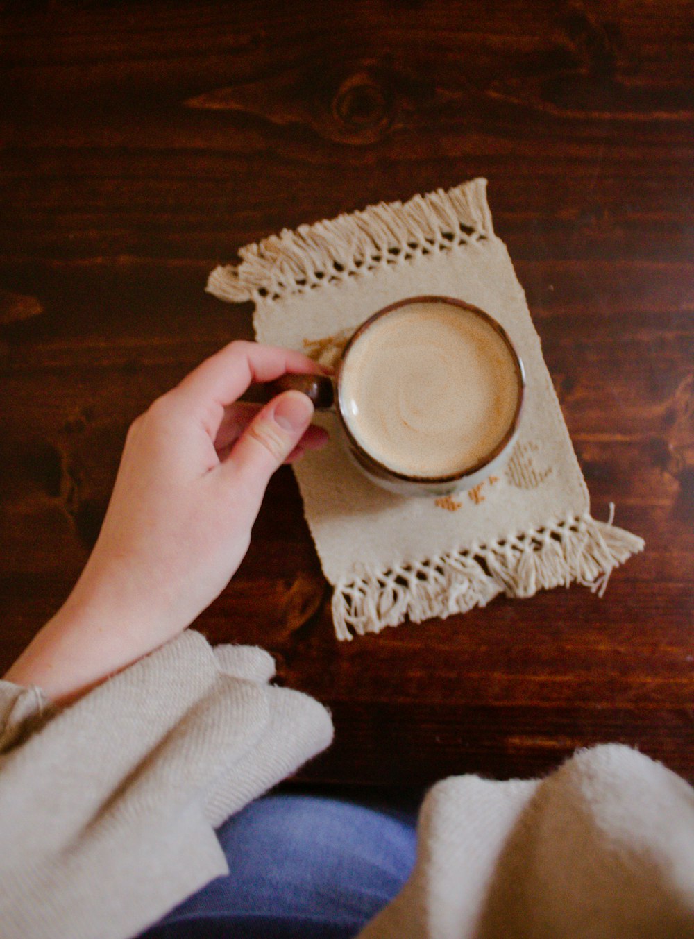 person holding white ceramic cup on brown wooden table