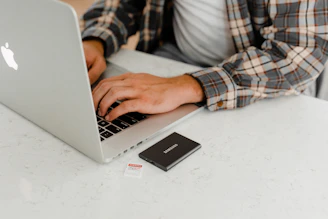person using macbook pro on white table