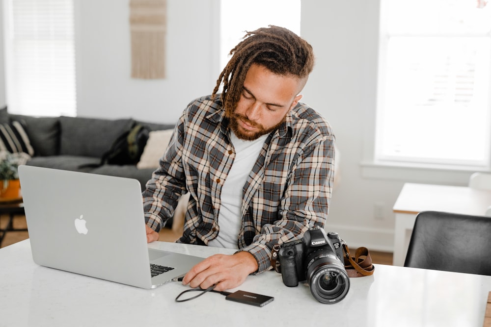 man in black and white plaid dress shirt using silver macbook