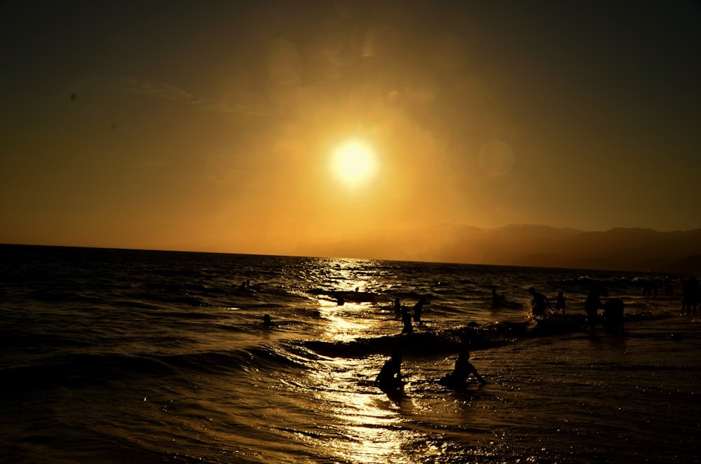 silhouette of 2 people standing on beach during sunset