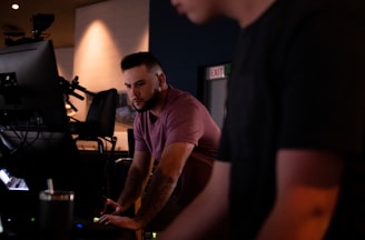 man in purple crew neck t-shirt standing near black flat screen tv