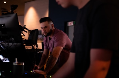 man in purple crew neck t-shirt standing near black flat screen tv
