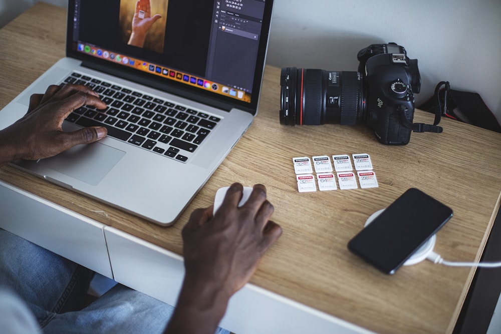 person using macbook pro on brown wooden table