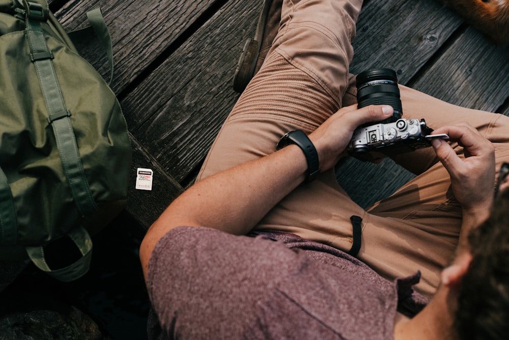 Persona en pantalones cortos marrones sosteniendo una cámara DSLR negra