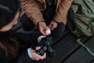 Close-up of hands exchanging a camera and a notebook, symbolizing collaboration in content creation.