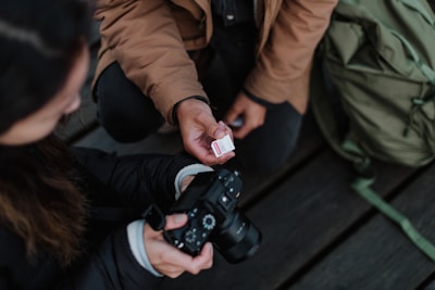 Close-up of hands exchanging a camera and a notebook, symbolizing collaboration in content creation.