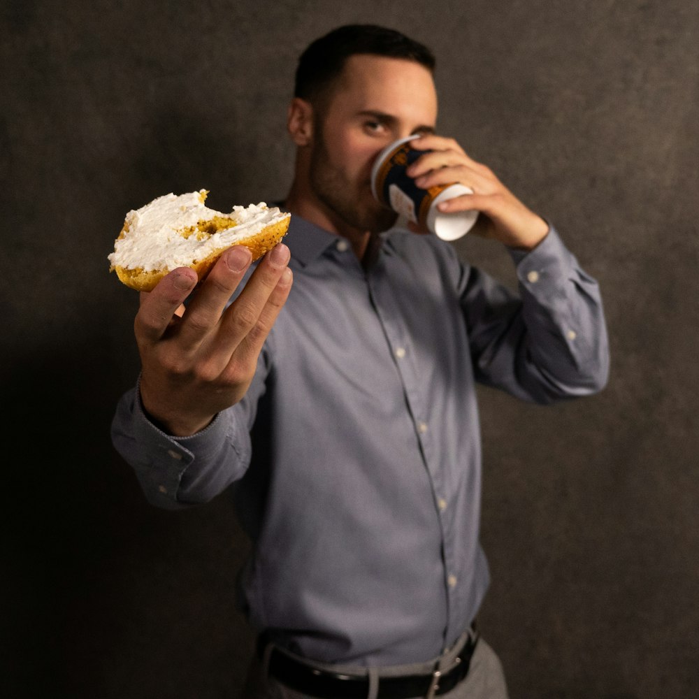 man in blue dress shirt holding bread