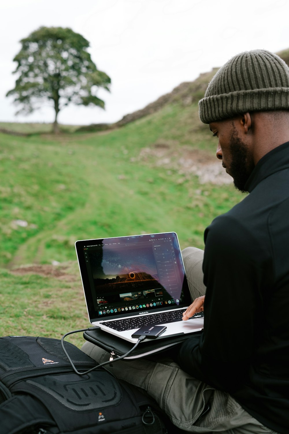 man in black jacket and brown knit cap using black laptop computer