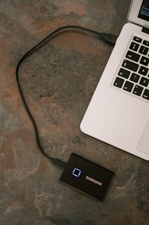An external SSD plugged into a laptop, showing fast data transfer in progress