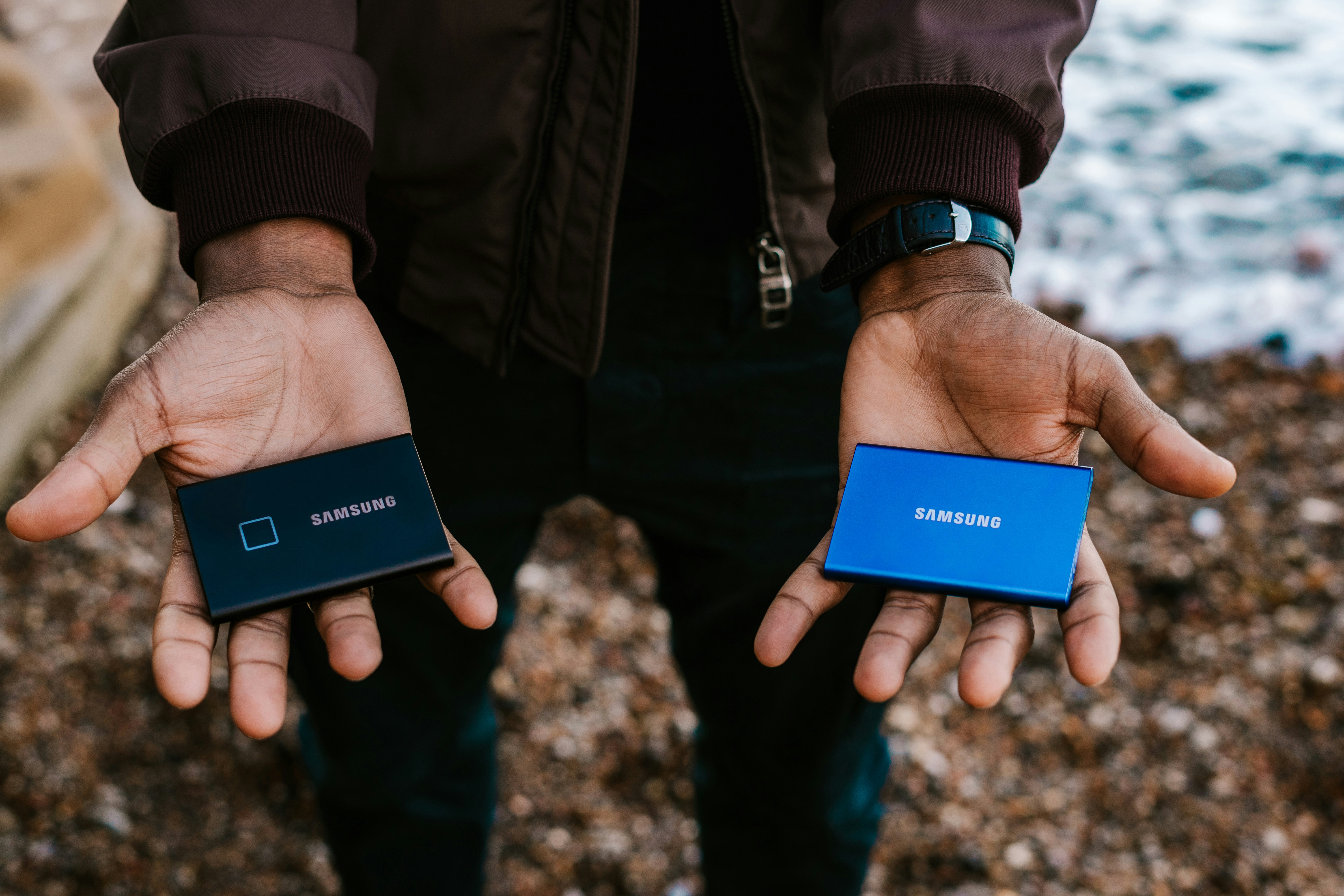 person holding blue and black portable SSD drives by Samsung