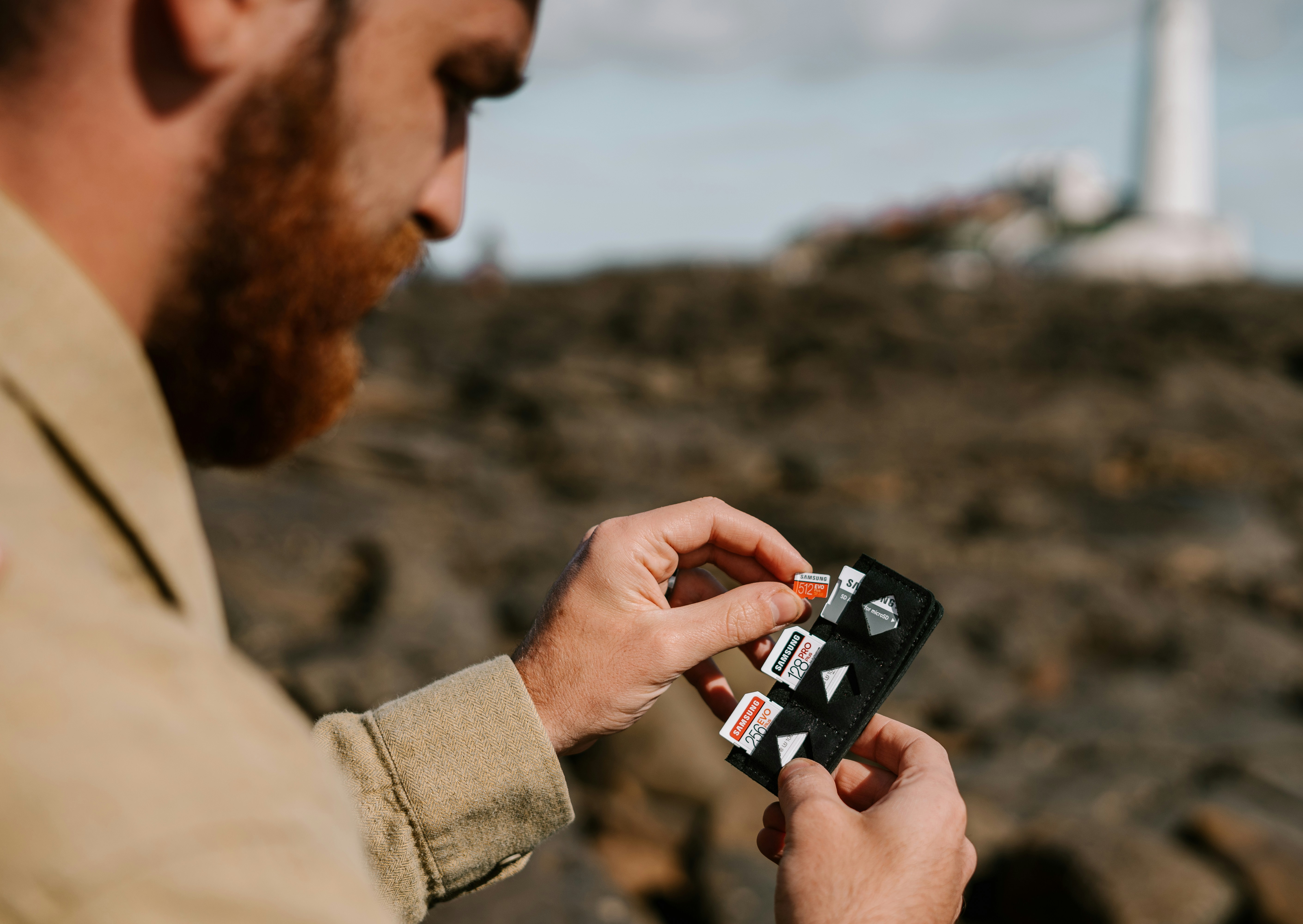 Man in brown coat holding black smartphone